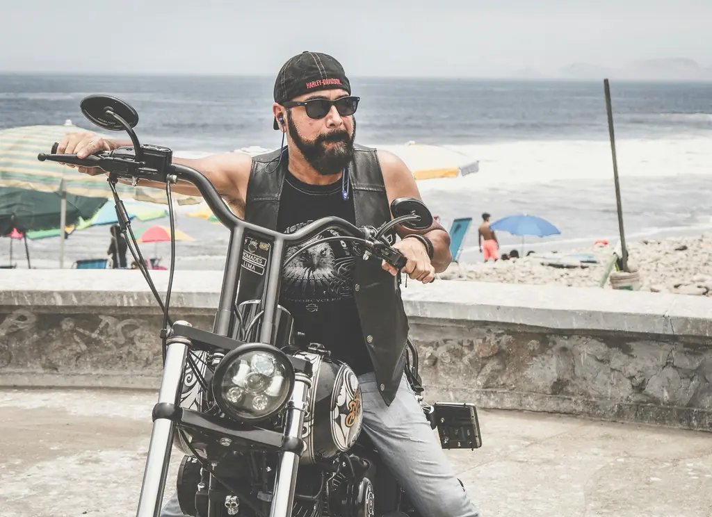 A rider in a bandana sits on his cruiser by the ocean